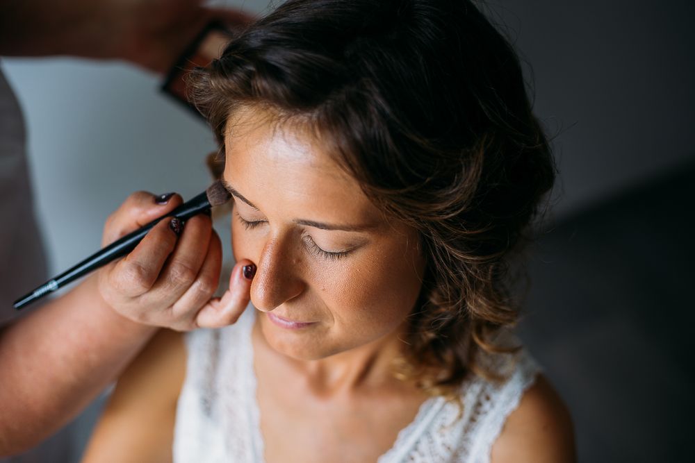Makeup artist applying eye makeup on wedding morning.