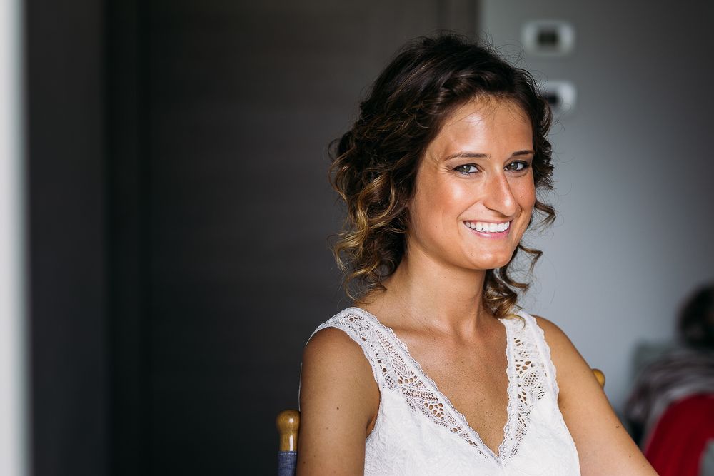 Elegant bridal portrait in white lace dress showing natural smile.
