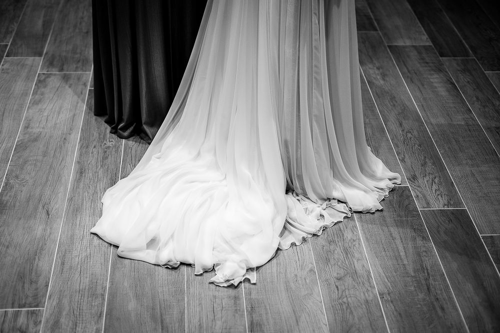 White wedding dress train with delicate lace details flows elegantly across wooden flooring.