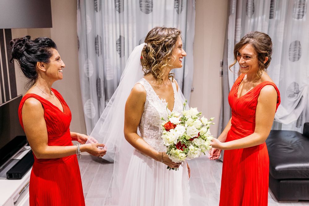 Wedding party members in red dresses assist with final preparations.