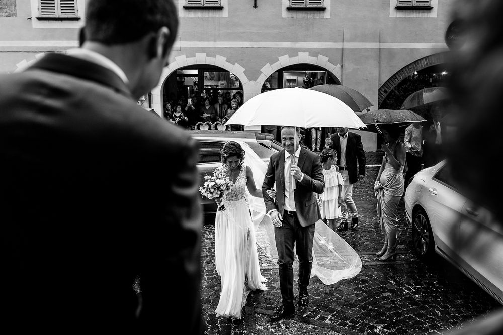 A black and white photo of a wedding ceremony entrance under white umbrellas.