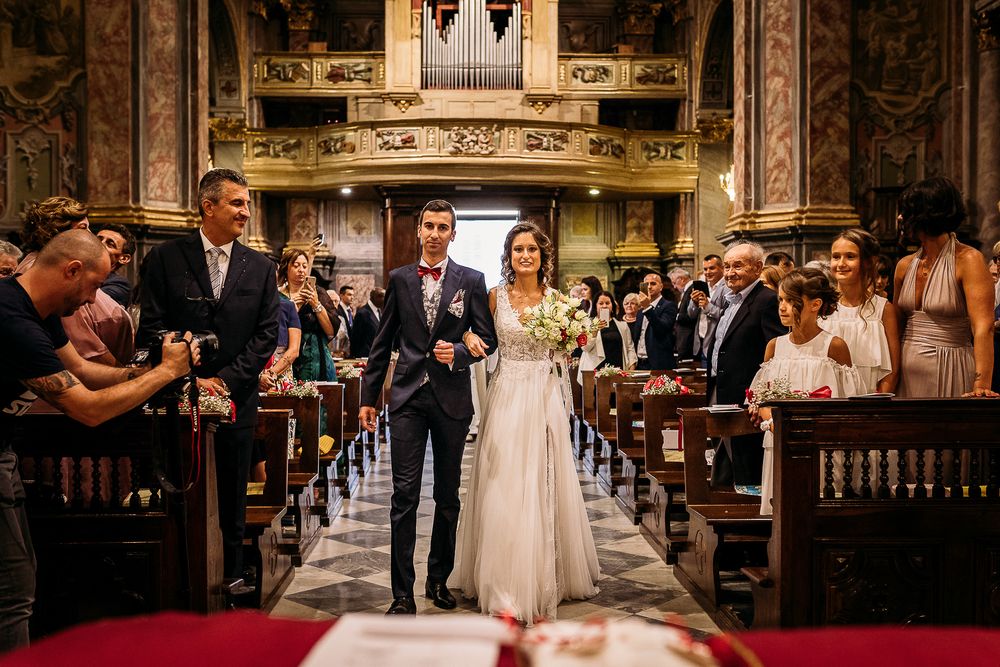 Wedding ceremony in progress inside an ornate cathedral with red carpet aisle.