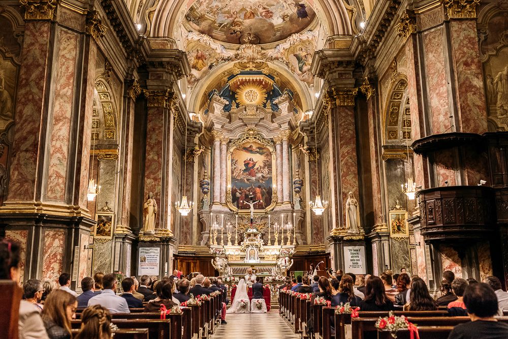 Stunning baroque church interior with painted ceiling and golden details during ceremony.