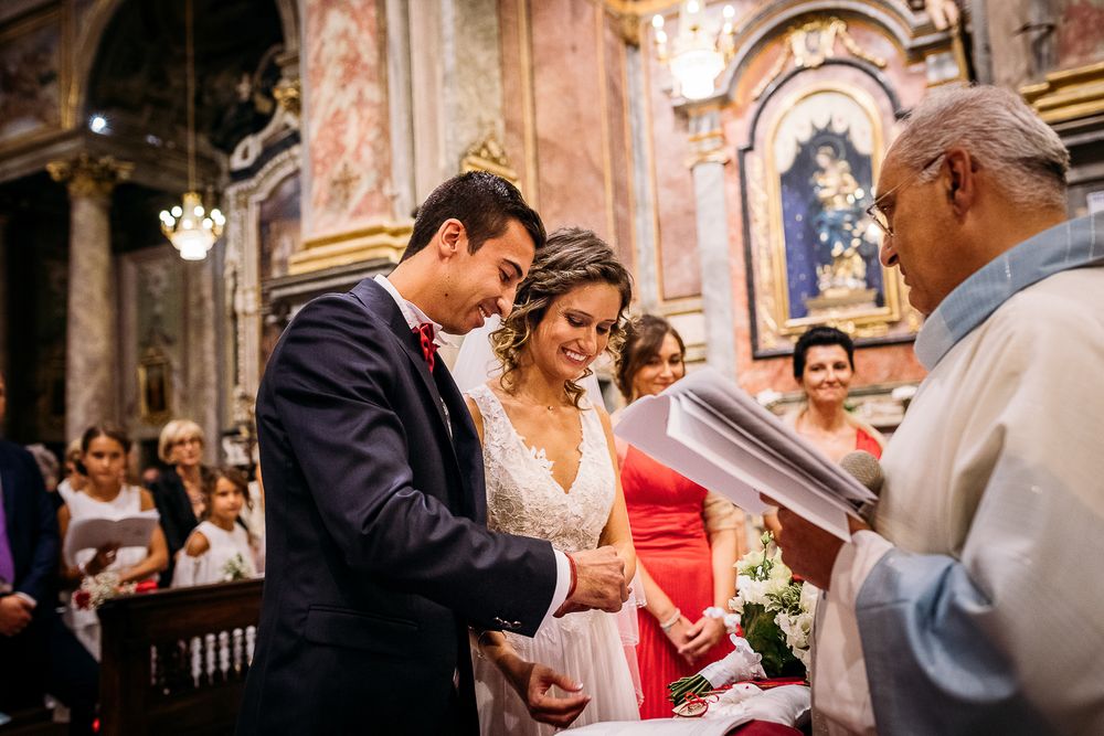 Wedding ceremony taking place in an ornate baroque church with priest officiating.