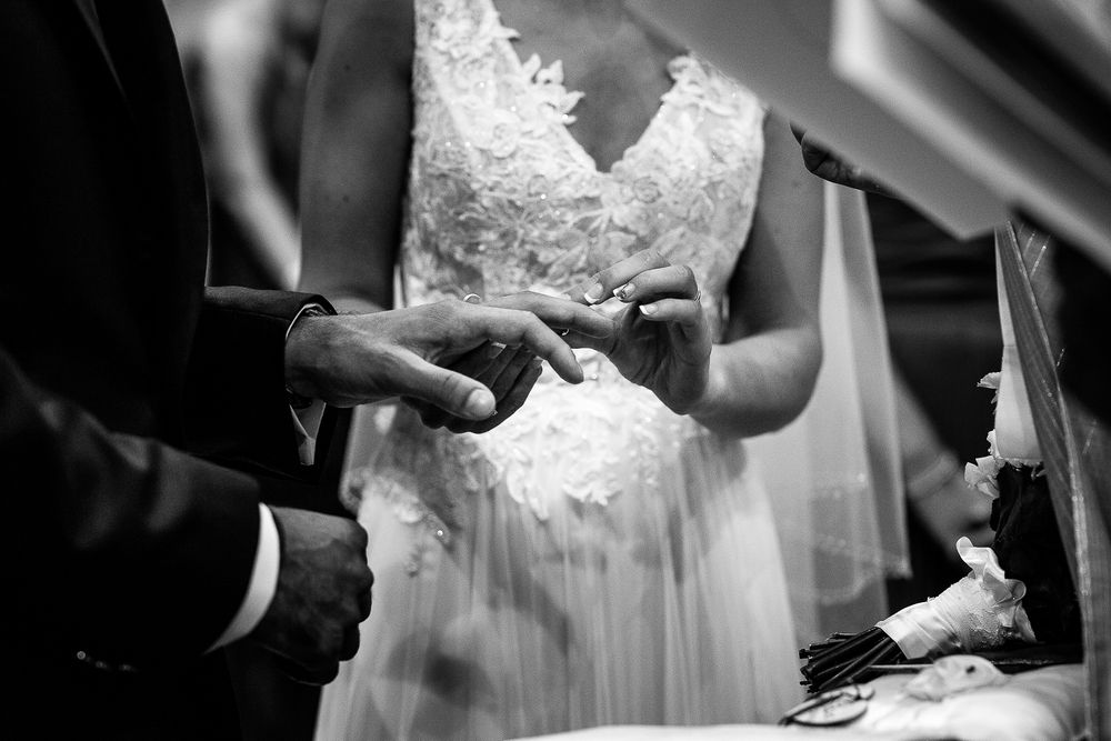 Black and white close-up of wedding ring exchange during ceremony.