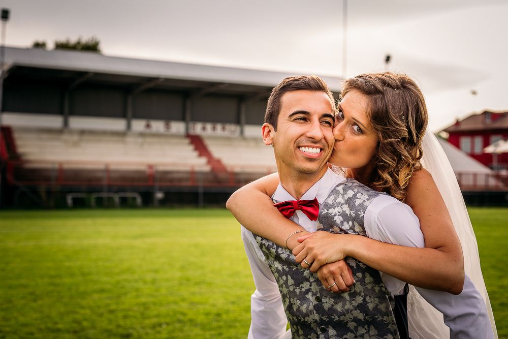 Romantic moment on sports field with couple in wedding attire.