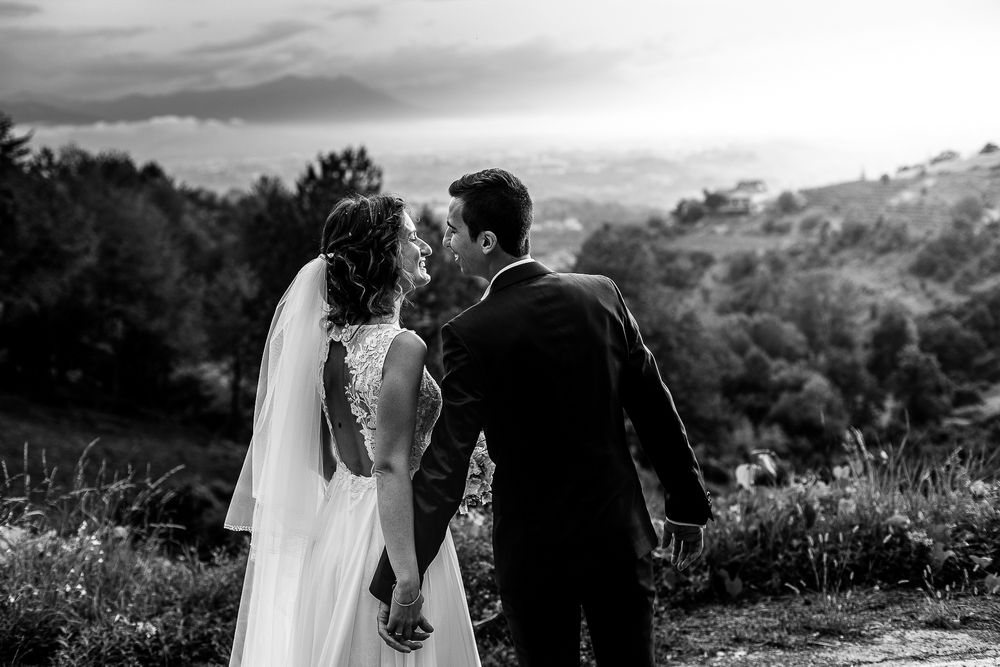 Scenic black and white portrait of a couple walking together on a hillside meadow.