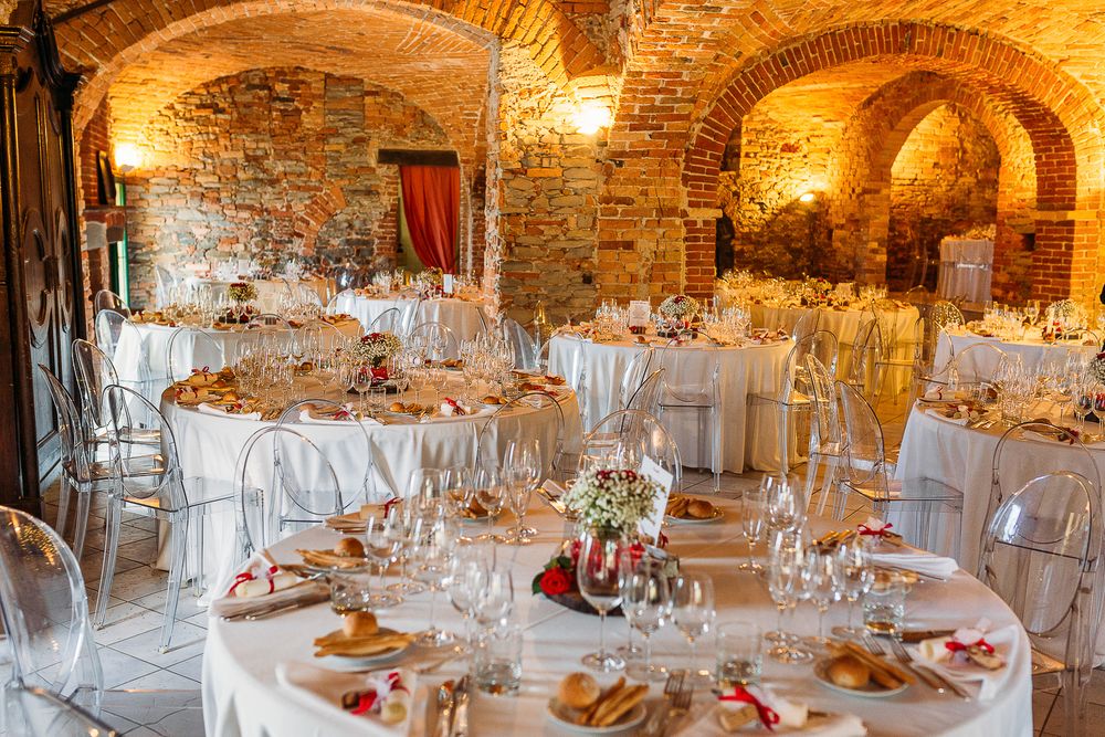 Elegant wedding reception setup in rustic stone cellar with round tables and white linens.