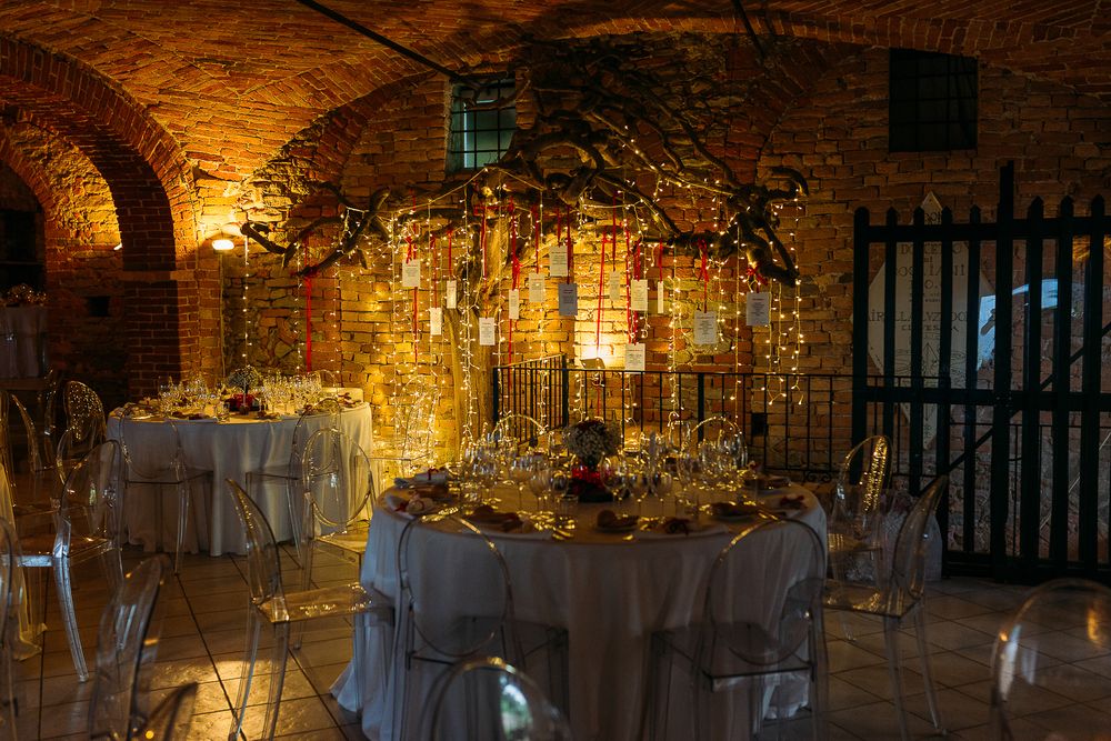 Romantic wedding table decor with fairy lights and greenery in stone cellar venue.