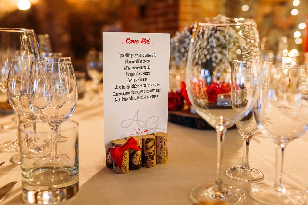 Wedding menu card displayed on decorated table with wine glasses and red accents.