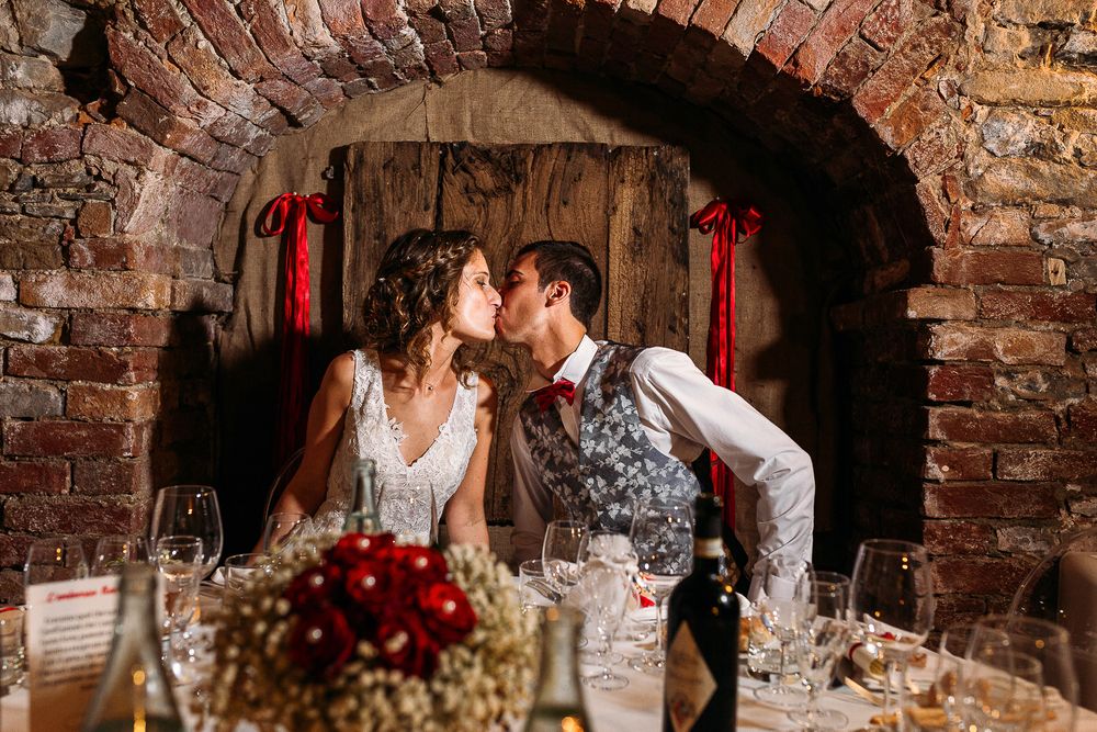 Romantic wedding scene in rustic brick archway decorated with red ribbons.