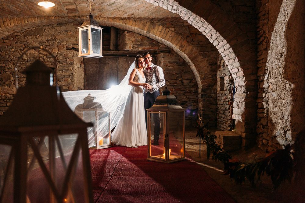 A romantic portrait in a wine cellar with stone arches and lantern decorations.