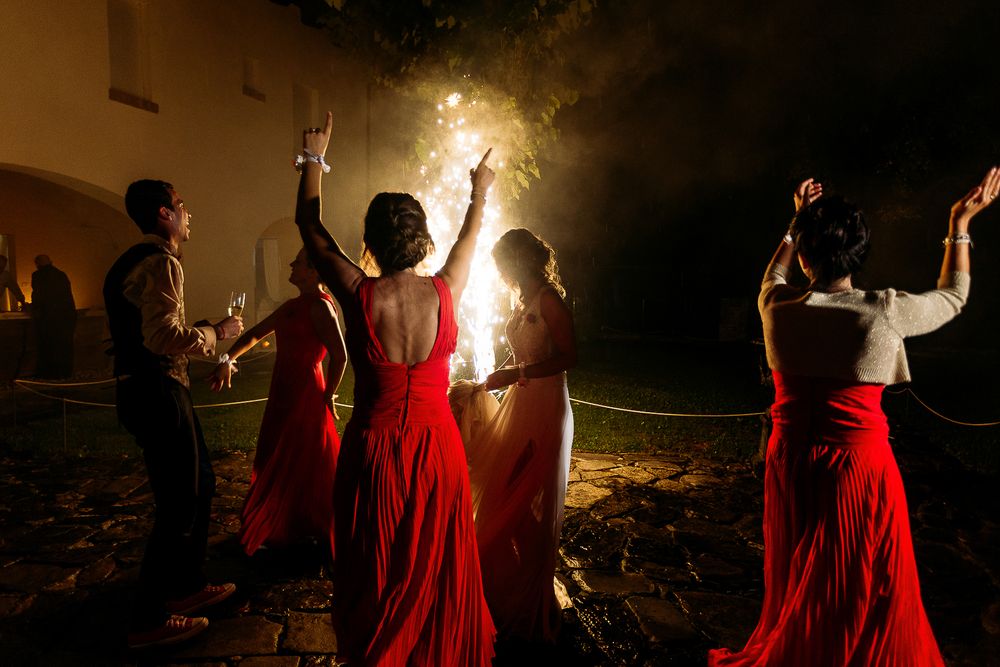 Wedding guests in red dresses dancing and celebrating at a nighttime reception.