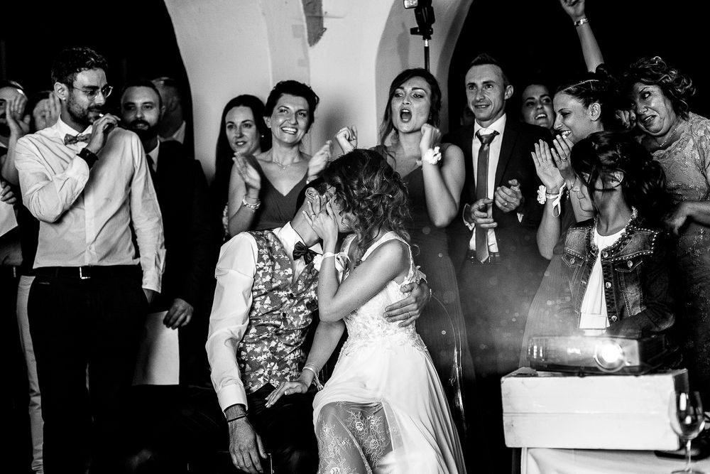 A black and white photo of wedding guests celebrating during a reception party.