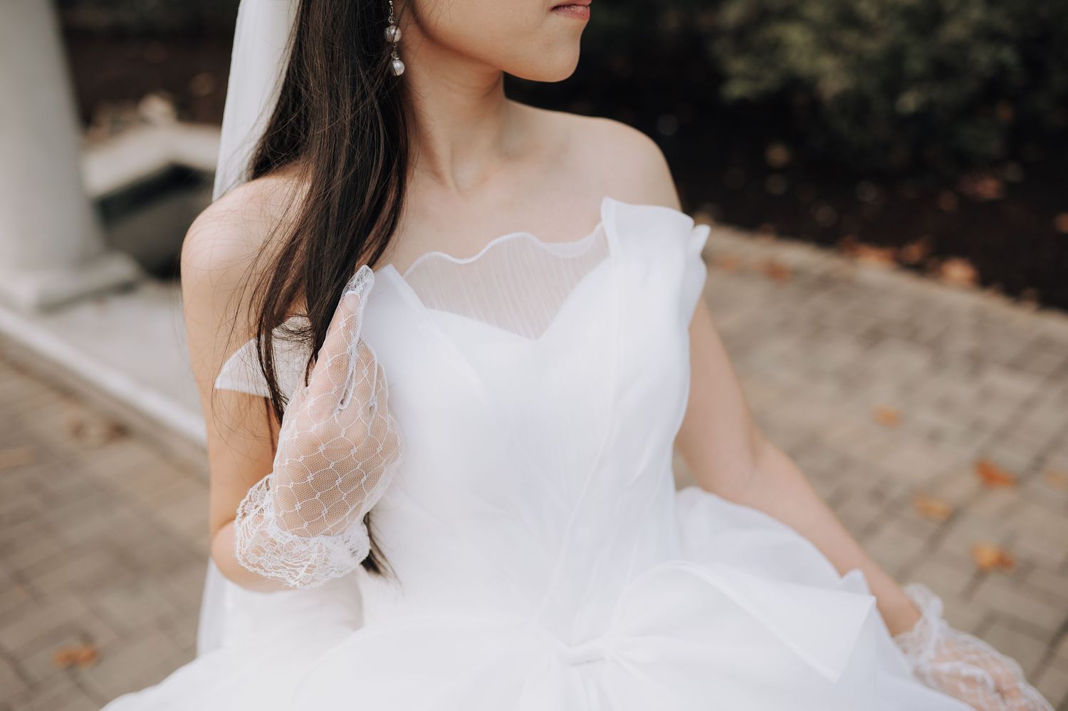Detail shot of bridal gown showing lace bodice and off-shoulder neckline design.