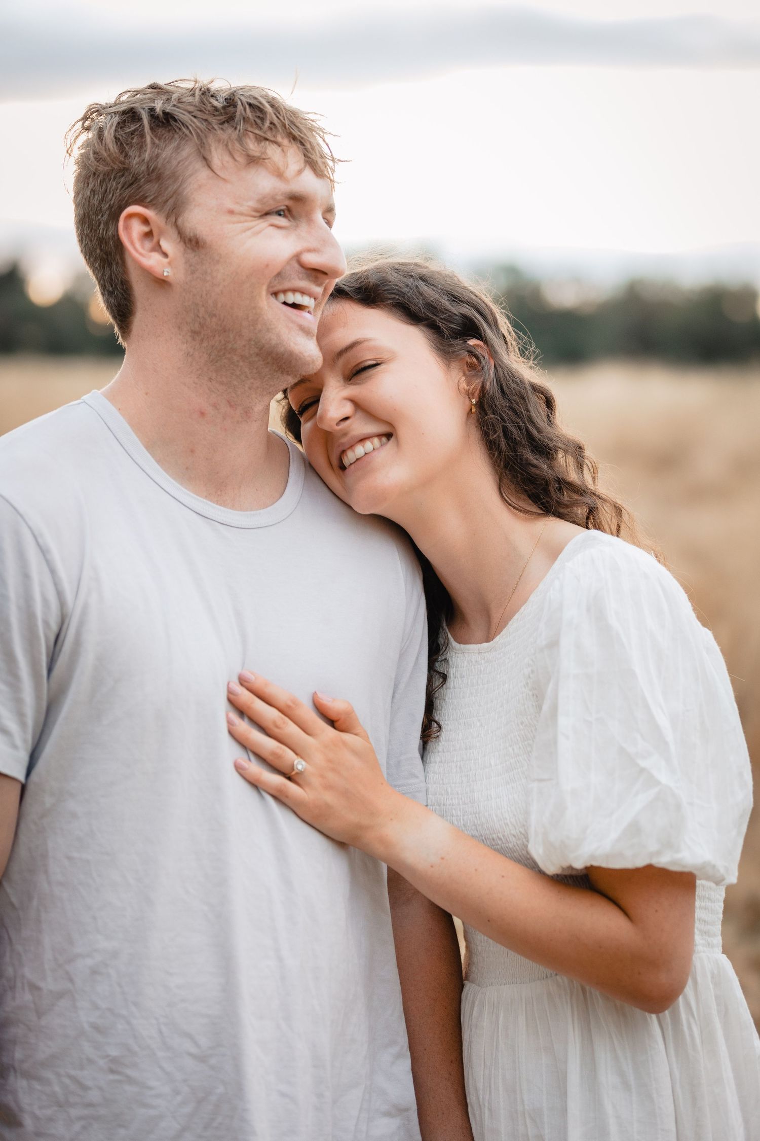 An intimate moment between a couple laughing together in soft natural lighting.