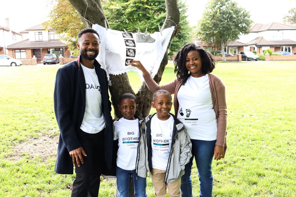 A family wearing matching t-shirts poses together on grass.