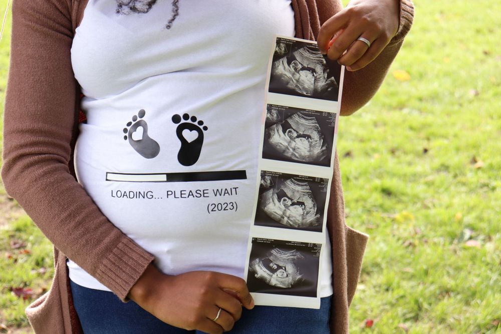 Close-up of a pregnancy announcement shirt with baby footprints and ultrasound images.