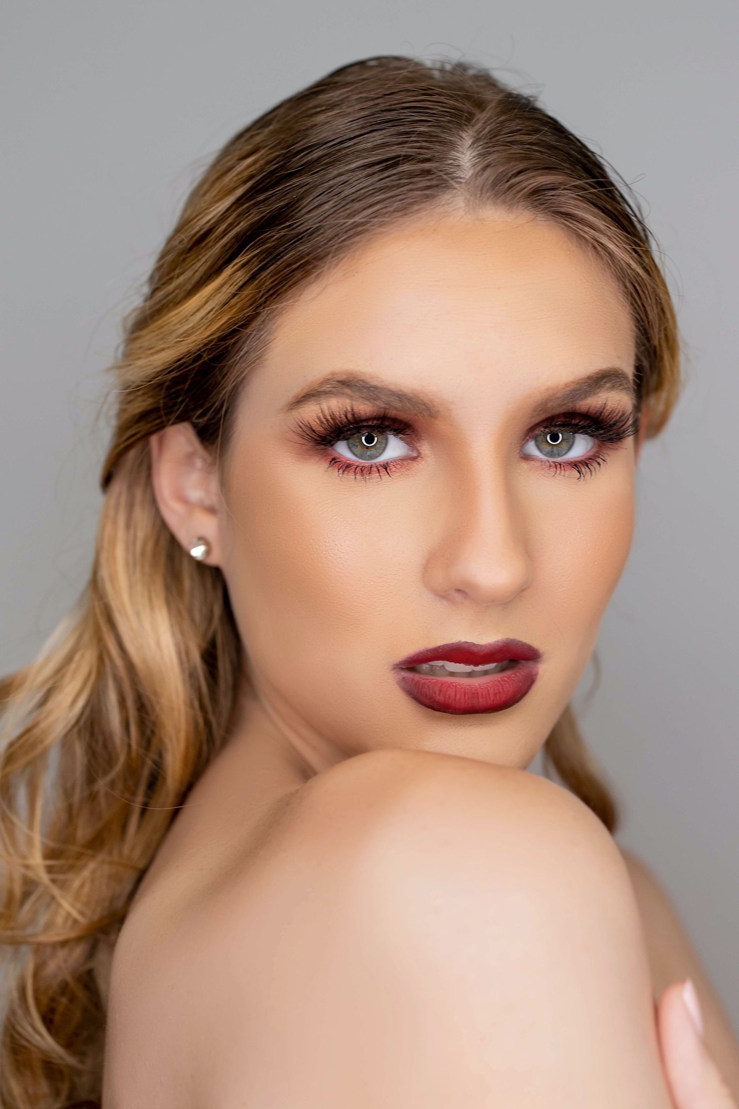 Beauty closeup featuring dramatic makeup, red lips, and blonde wavy hair styled to one side.