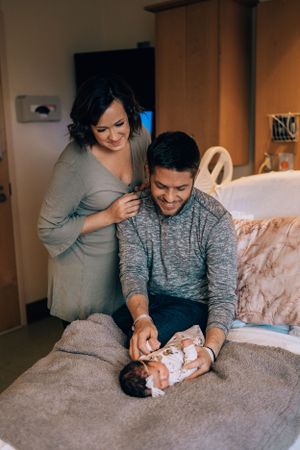 Parents sharing a tender moment with their newborn on a cozy bed.