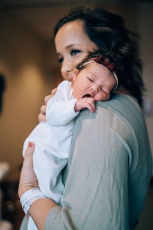 Sweet interaction between parent and crying newborn in hospital room.