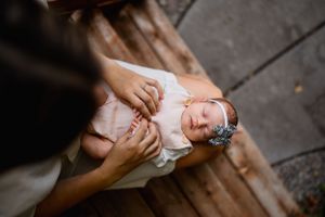 Overhead view of sleeping newborn in white outfit on wooden surface.