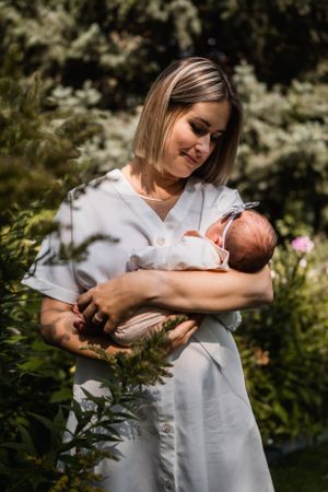 A tender newborn photoshoot featuring gentle embraces and soft lighting in an outdoor garden setting.