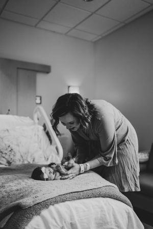 A tender moment in black and white of a parent resting close to their newborn.