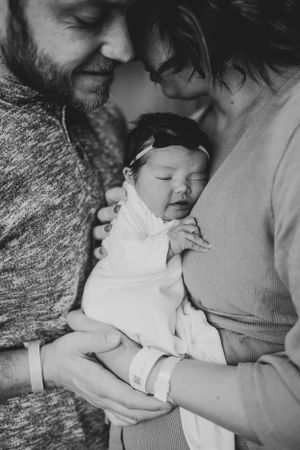 Black and white portrait of tender moment between parent and sleeping newborn.
