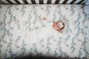 Soft floral wallpaper creates delicate backdrop for intimate family photography session.