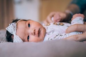 Intimate close-up portrait of a baby lying on soft bedding.