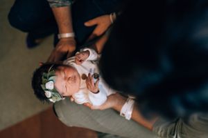 Close-up view of hands gently holding a swaddled newborn baby.
