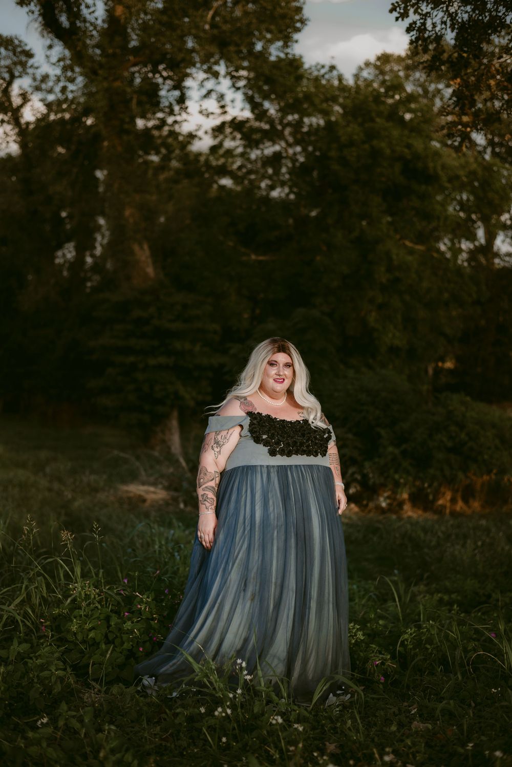 Outdoor portrait featuring a dramatic blue and black gown against a wooded backdrop.