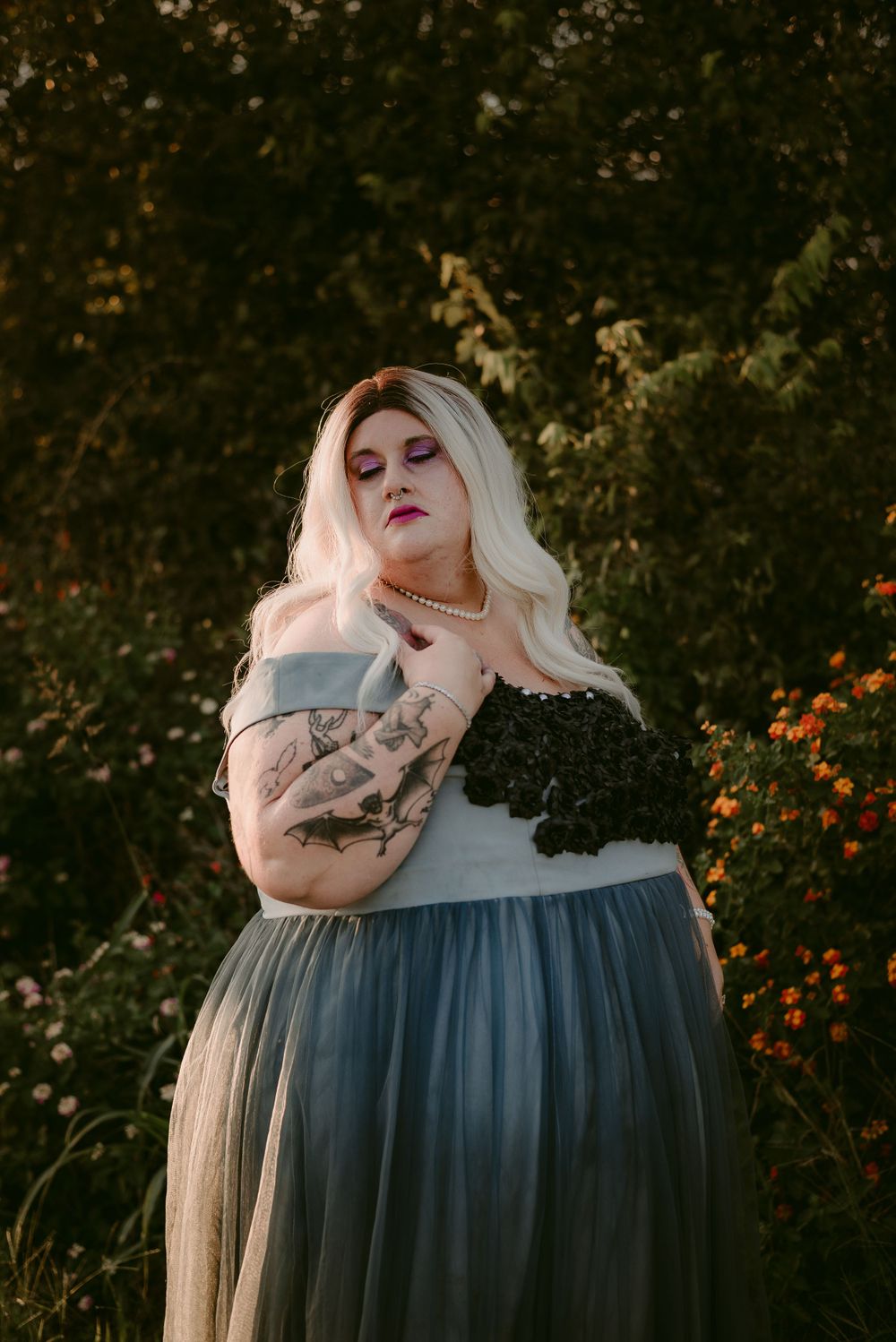 Artistic portrait featuring tattoos and a dramatic blue and black formal gown.
