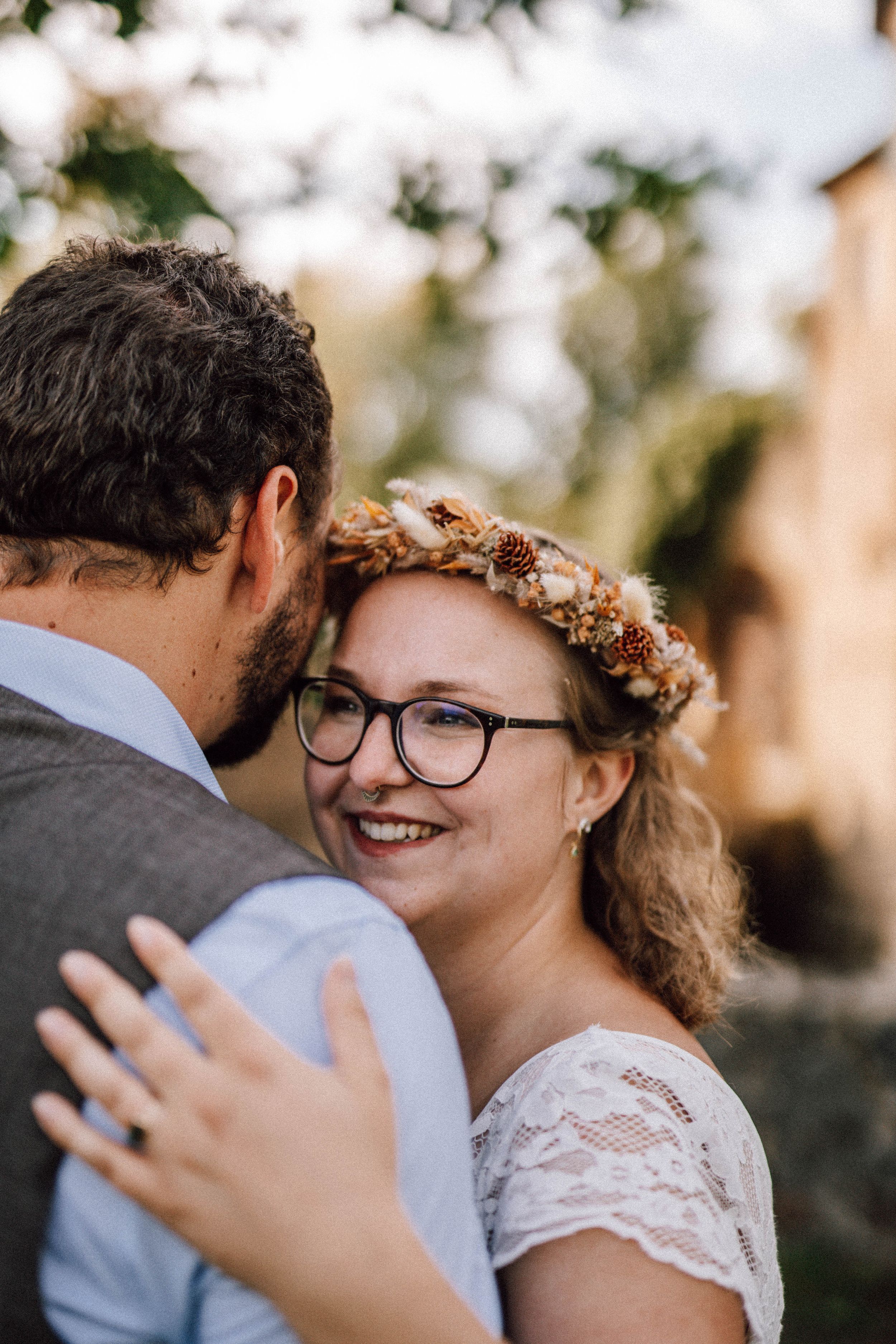 Intimate wedding moment captured in natural lighting with lace dress details.