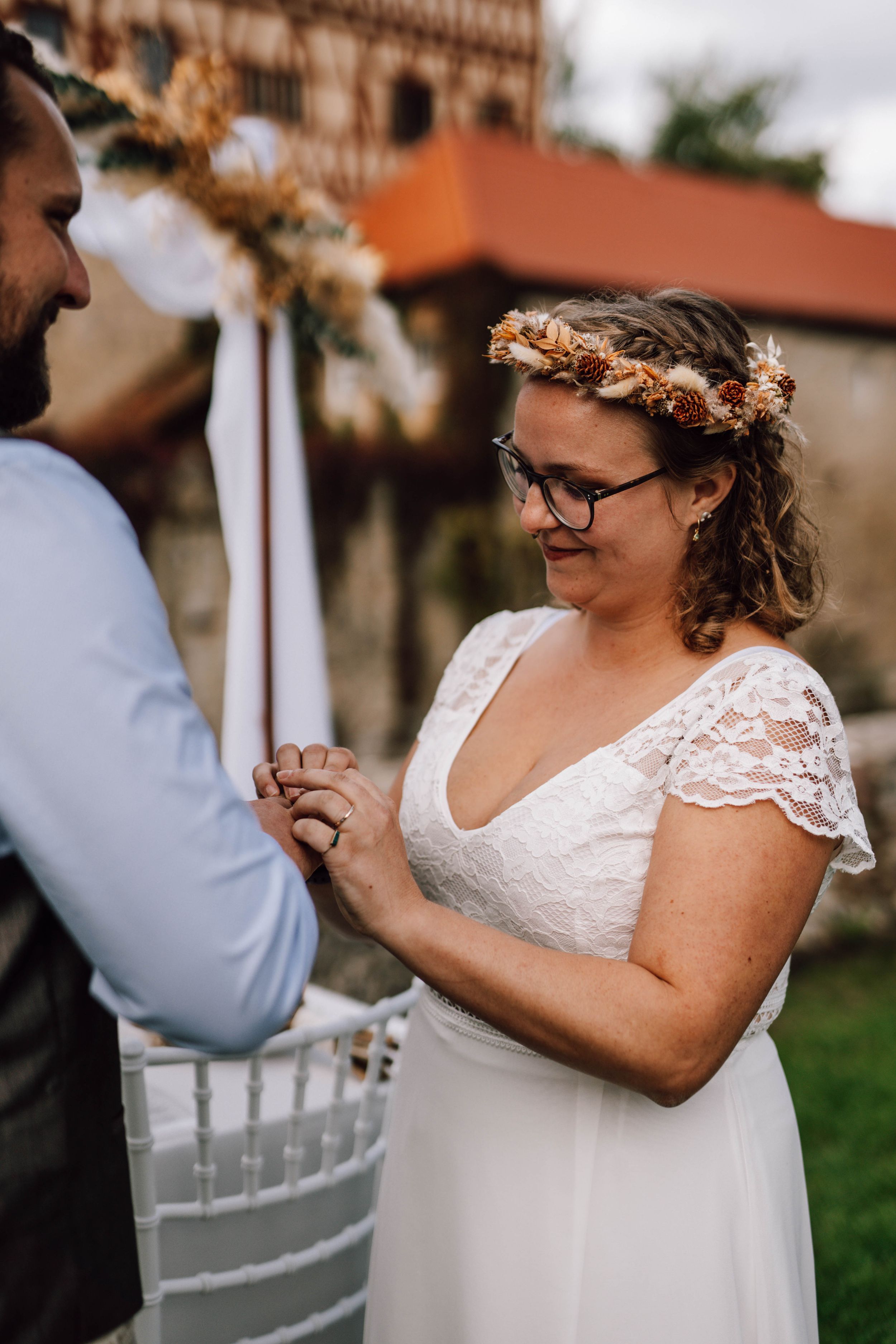 Intimate moment during outdoor wedding ceremony with stone building in background.