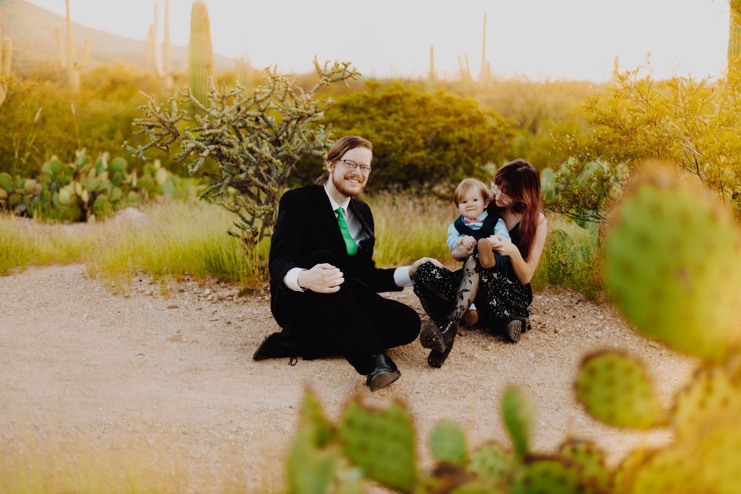 Group sitting outdoors among desert plants during sunset.