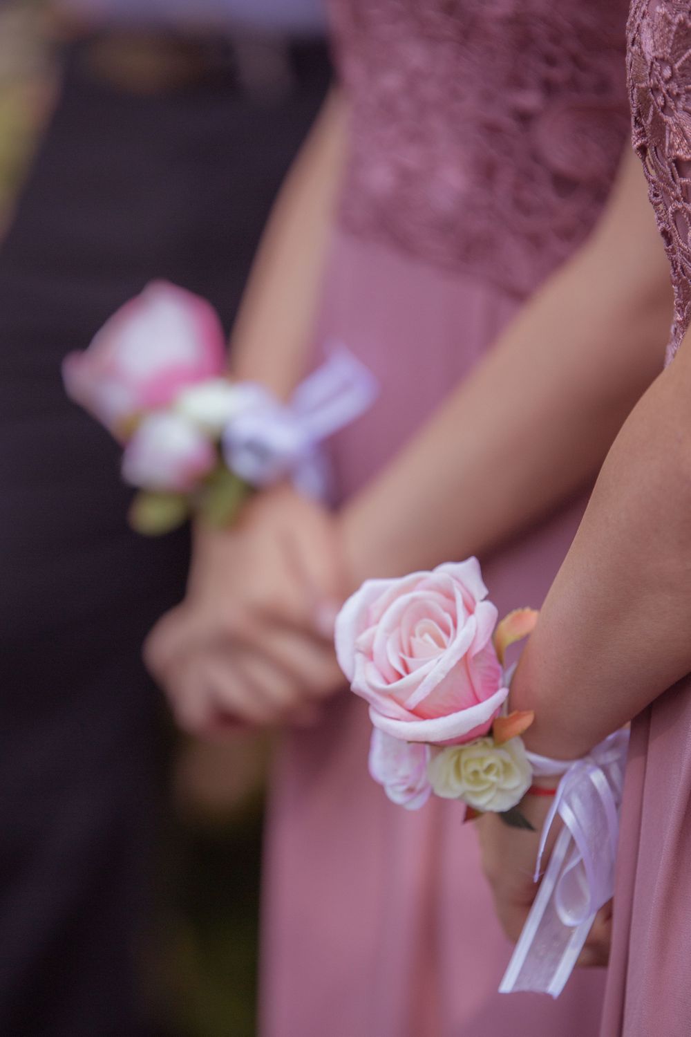 Delicate pink rose wrist corsages worn with dusty rose bridesmaid dresses.