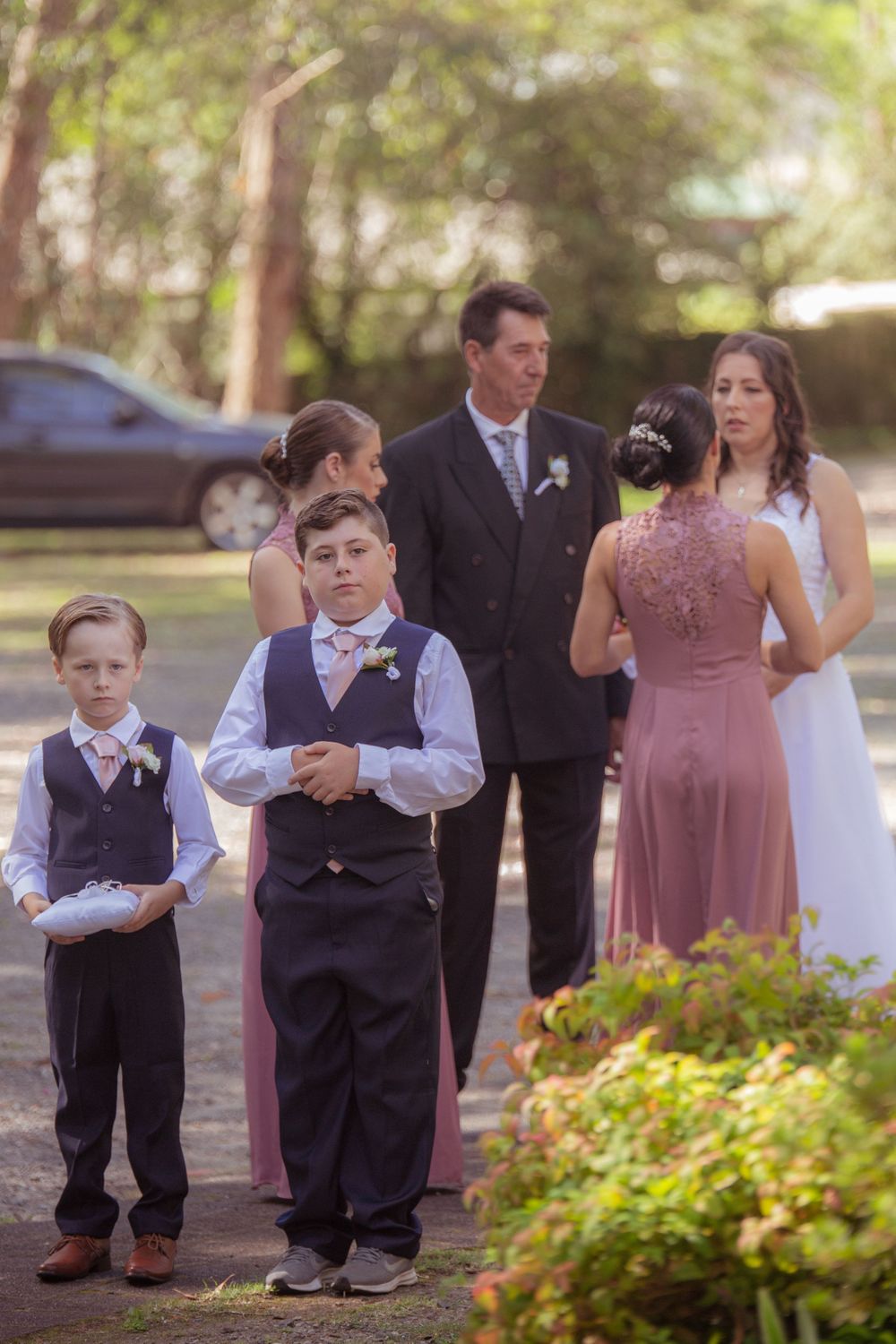 Wedding party lineup including young attendants in formal wear outdoors.