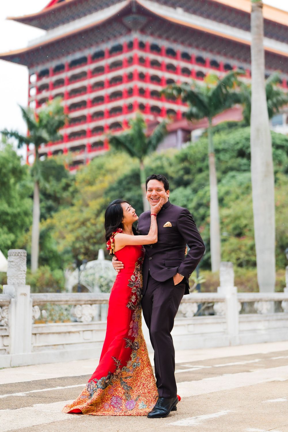 Dancing couple in formal attire with traditional Chinese architecture in background.