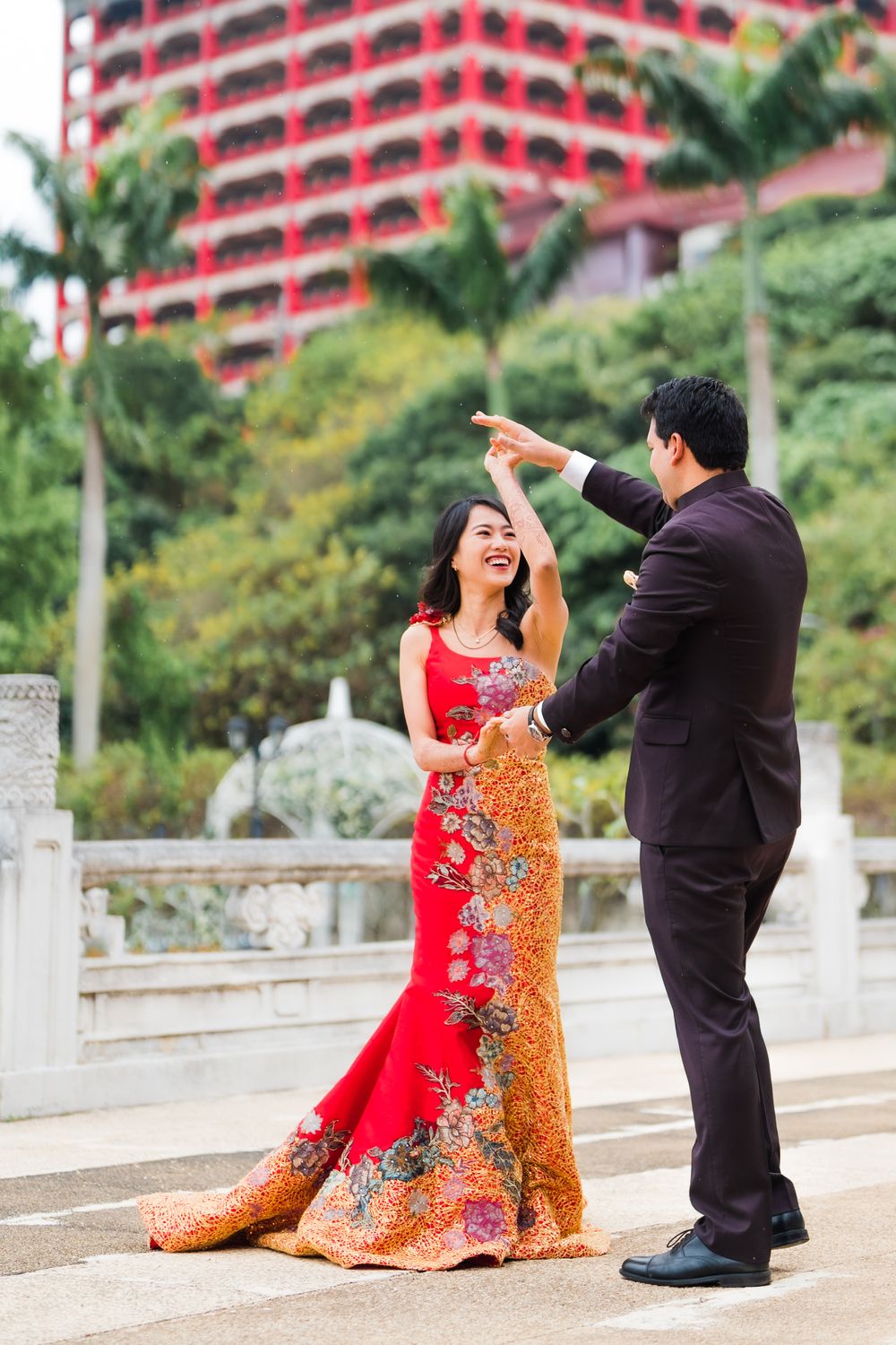 A couple dances together outside the Grand Hotel with its distinctive red architecture in the background.