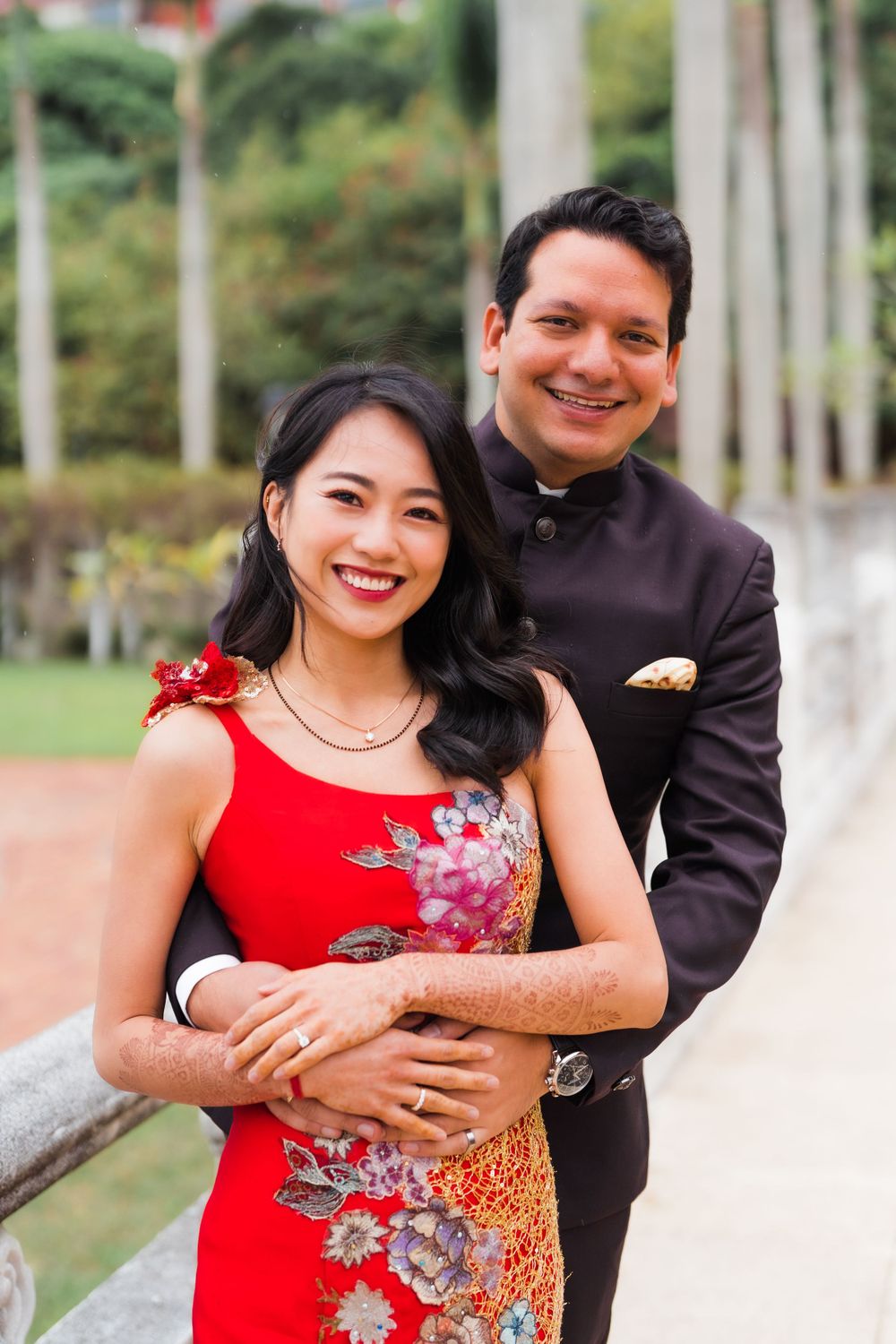 A couple embraces while posing for a portrait outside a traditional Asian building.