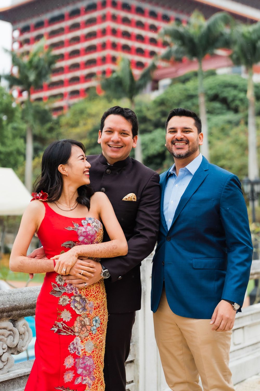 Three friends share a joyful moment outside the Grand Hotel in Taipei with its iconic architecture.