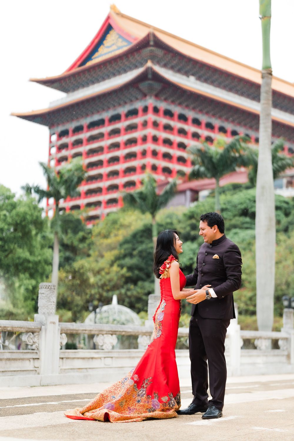 A couple shares a romantic moment outside an iconic Asian pagoda-style building.
