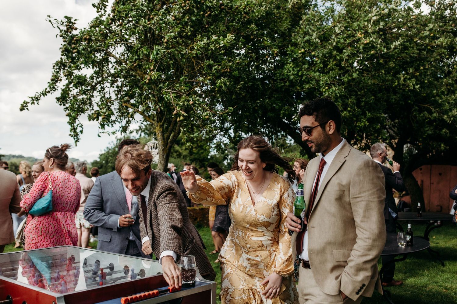 Wedding guests interact around vintage gaming equipment at an outdoor reception.