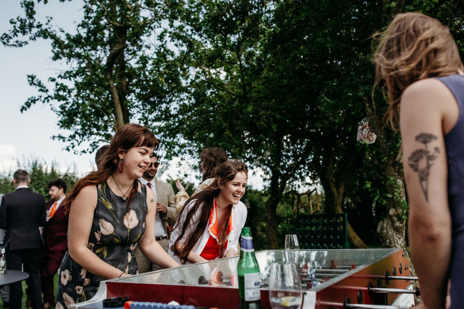 Guests gather around a vintage gaming table at an outdoor party.