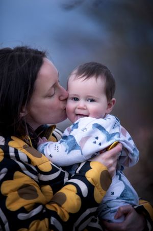 A tender moment between adult and baby sharing a kiss while wearing colorful patterned clothing.