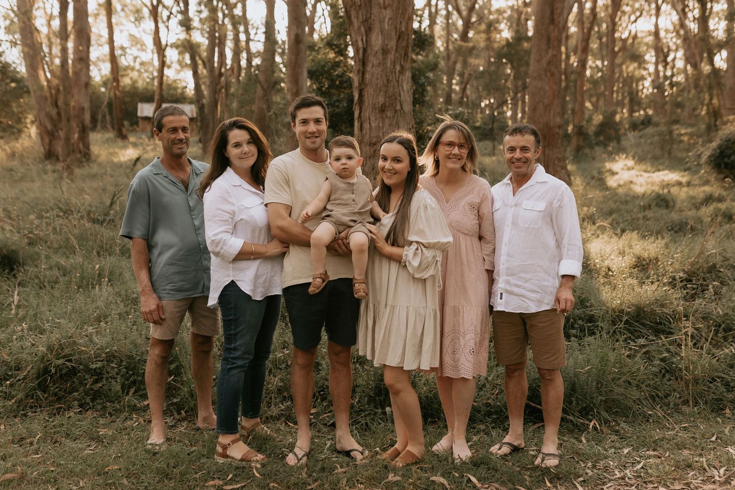 Extended family gathering outdoors in neutral colored outfits for professional photos.