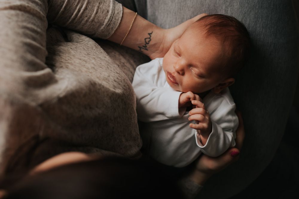 mama trzyma noworodka - sesja rodzinna Kraków