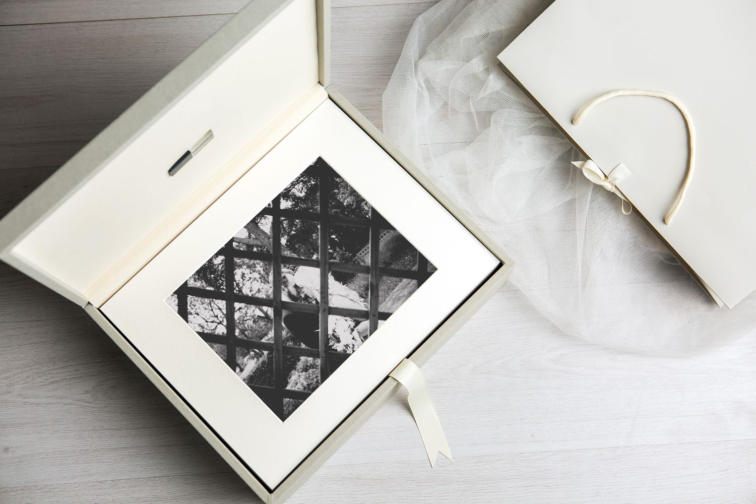 Styled detail of an opened ultimate presentation box with fine art prints finished in ivory faux leather.